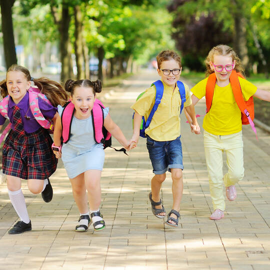 small schoolchildren with colorful school bags and backpacks run to school.
