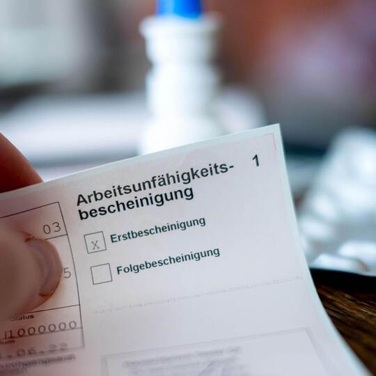 Eine Person hält eine Arbeitsunfähigkeitsbescheinigung
