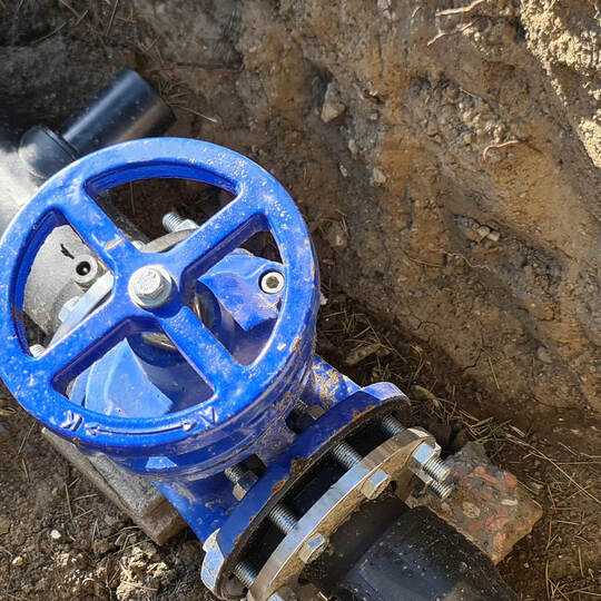 Blue faucet to control sewerage system in ground.