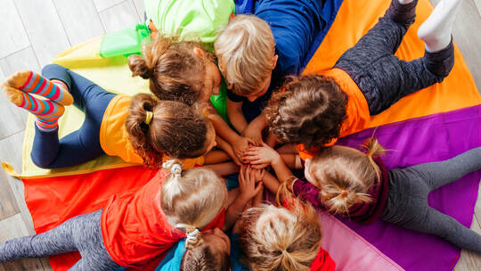 Cheerful children playing team building games on a floor