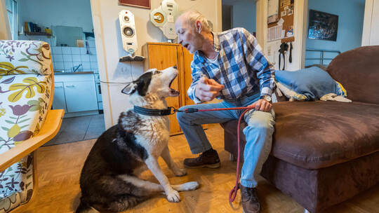 Sie kommunizieren in ähnlicher Körperhaltung: Marco G. mit seinem Malamute-Mischling „Bubberle“ in seiner Notunterkunft. Der Hun