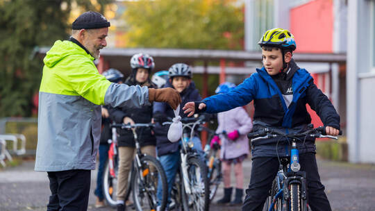 Ein gefülltes Säckchen gibt Ulrich Dörsch beim Radtraining an der Südstadtschule dem achtjährigen Ibrahim in die Hand. Er soll e