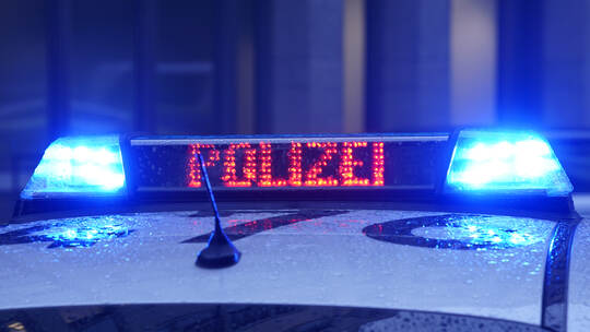 Ein Polizeiauto steht vor einem Gebäude (Symbolbild)
