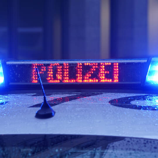 Ein Polizeiauto steht vor einem Gebäude (Symbolbild)
