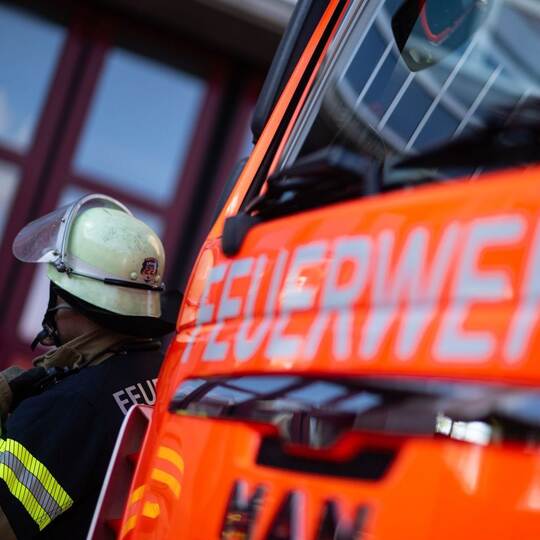 Feuerwehrmann steht neben einem Feuerwehrauto (Symbolbild)