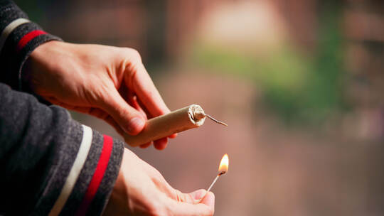 Close up of man hand lighting up a firecrackers in a burred background