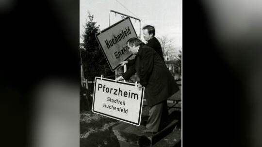 Symbolträchtiger Schilderwechsel: Huchenfelds Gemeinderat Hugo Sorg (links) und Pforzheims OB Dr. Willi Weigelt tauschen am 1. J