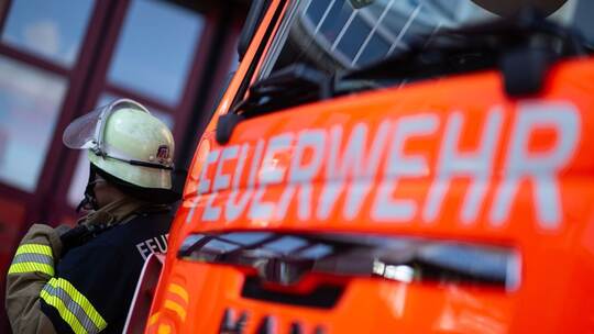 Feuerwehrmann steht neben einem Feuerwehrauto (Symbolbild) Feuerwehrmann steht neben einem Feuerwehrauto (Symbolbild)