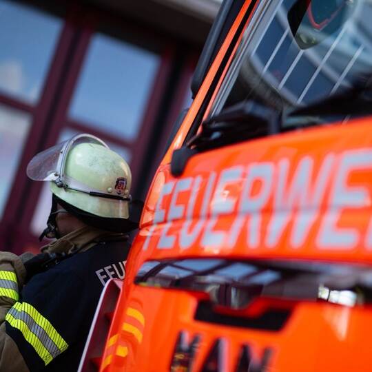 Feuerwehrmann steht neben einem Feuerwehrauto (Symbolbild)