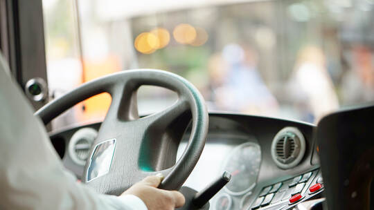 cropped shot of bus driver holding steering whee