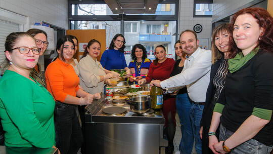 Die Frauen des Integrationskurses kochen mit Helfern aus Verwaltung uns Politik in der Küche des Familienzentrums leckere landes