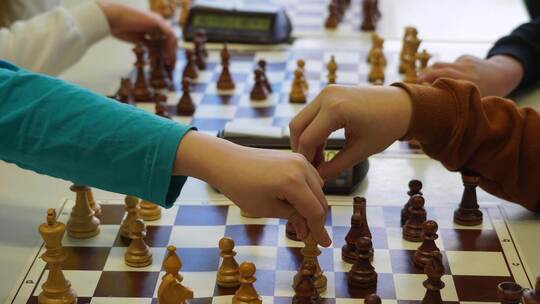 D ass an einem Brett zwei Hände gleichzeitig greifen, ist beim Schach nic ht vorgesehen. Doch für das Pressefoto machen die Schü