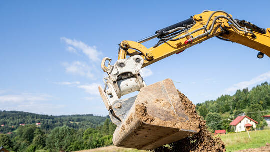 Mini excavator digging preparing ground under home garden