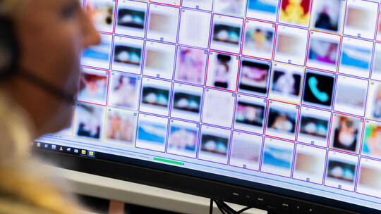 Eine Ermittlerin sitzt vor Monitoren mit unkenntlich gemachten Fotografien, die teilweise sexuellen Missbrauch zeigen. Rolf Venn Hinweistelefon für sexuellen Missbrauch von Kindern