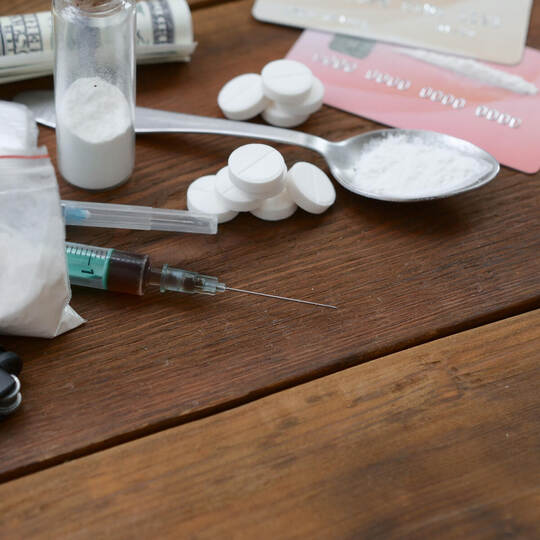 A lot of narcotic substances pills and devices for the preparation of drugs lie on an old wooden table