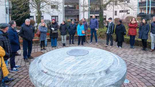 Ortsvorsteher Siegbert Morlock (vierter von links) erklärt am Brunnen in der Dorfmitte die geplanten Umgestaltungen des Platzes.