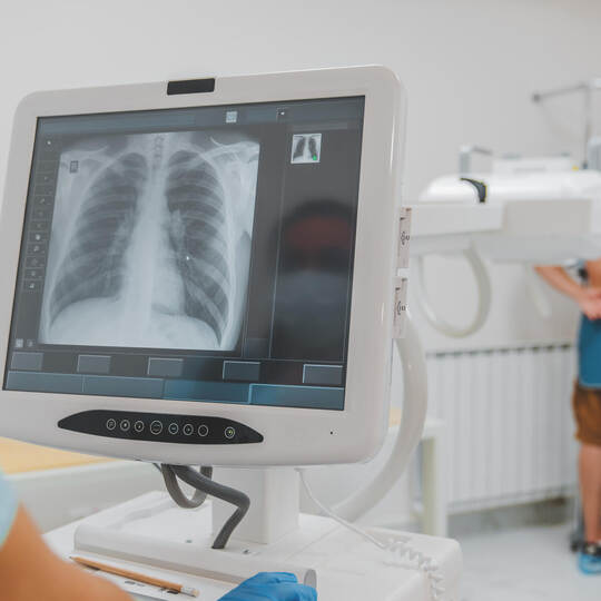 Young caucasian man standing against wall while doctor using X-Ray machine scan him in hospital