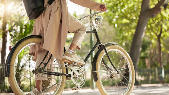 Bicycle, closeup and feet of casual cyclist travel on a bike in a park outdoors in nature for a ride or commuting. Exercise, wel