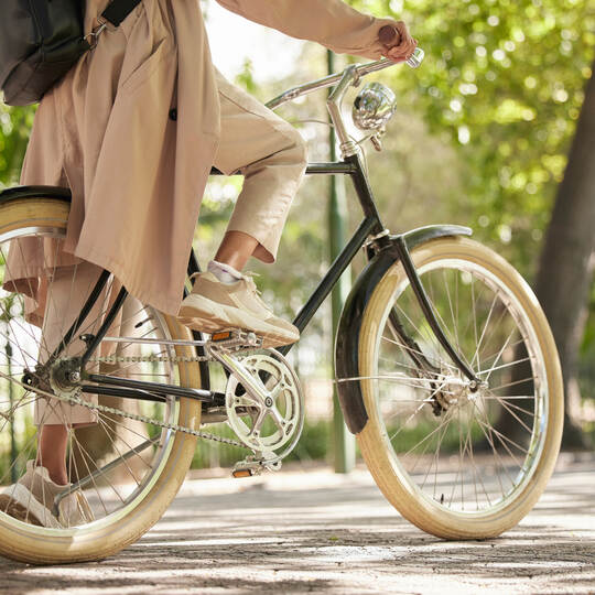 Bicycle, closeup and feet of casual cyclist travel on a bike in a park outdoors in nature for a ride or commuting. Exercise, wel