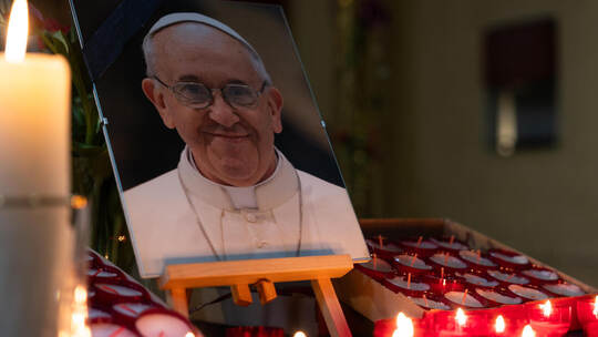 In Pforzheims Herz-Jesu-Kirche leuchten von Gläubigen entzündete Kerzen vor einem Bild des verstorbenen Papstes Franziskus. Papst Franziskus Gedenken Herz Jesu