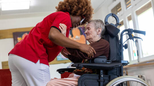 Gelernt ist gelernt: Um dieser Seniorin aus dem Rollstuhl aufzuhelfen, setzt die 24-jährige Emmanuelle Noah aus der kamerunische Reportage Pflegekraft Kamerun