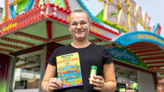 Sabrina Seyfert mit dem Buch und Buntstifte-Set, das Kindern gratis Abwechslung bringt. Mess Seyferts Cocktail Kindermalen