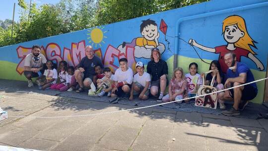 Freuen sich über den neuen bunten Hingucker am Kinder- und Familienzentrum Dillweißenstein: Kinder zusammen mit Graffiti-Künstle