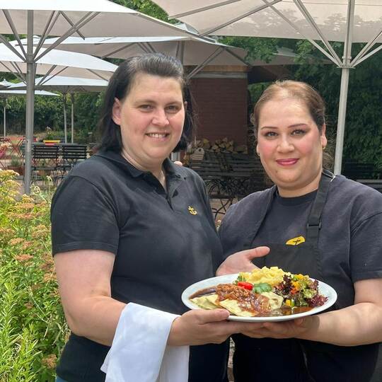 Sie präsentieren die klassischen „Ankertaschen“ im Garten des Restaurants: Nicole Below und Nasreen Adel Ali (von links). Seit e