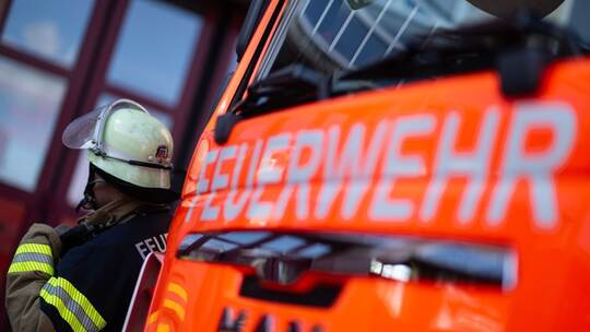 Feuerwehrmann steht neben einem Feuerwehrauto (Symbolbild)