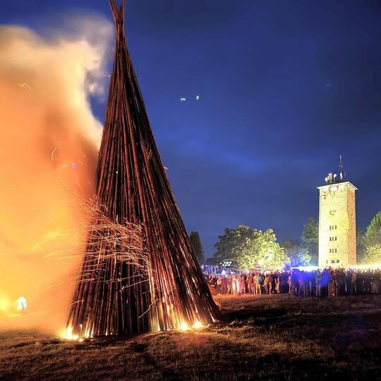 Zahlreiche Besucher verfolgen das Entzünden des Holzstoßes.