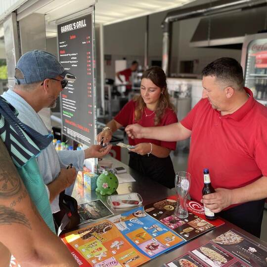 Die eine gibt das Wechselgeld, der andere die Ware – in dem Fall ein Bier: Aushilfe Letizia mit Kioskbetreiber Gabriel Jiranov i