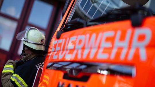 Feuerwehrmann steht neben einem Feuerwehrauto (Symbolbild)