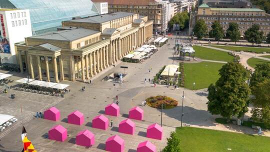 Zwölf Magenta-farbene Häuser stehen eine Woche am Stuttgarter Schlossplatz.