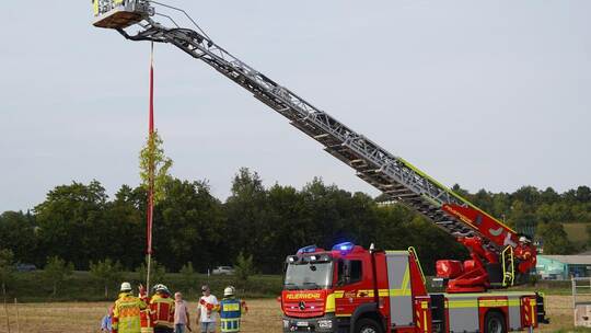Mit der großen Drehleiter hievt die Königsbach-Steiner Feuerwehr den Baum in das Loch, das der Bauhof bereits ausgebaggert hat.