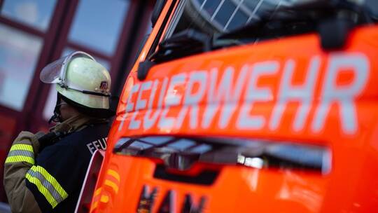 Feuerwehrmann steht neben einem Feuerwehrauto (Symbolbild) Feuerwehrmann steht neben einem Feuerwehrauto (Symbolbild)