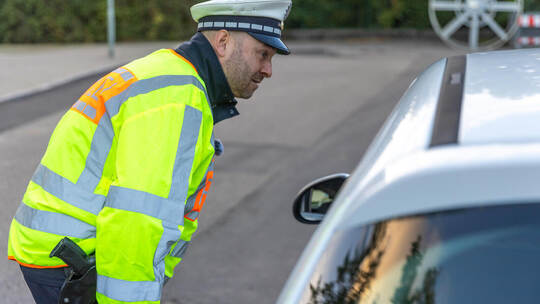 Polizeihauptkommissar Kay Erlenmayer erklärt der Autofahrerin, wieso sie künftig besser nicht bis vor das Schulgebäude der Arlin Kontrollaktion Arlingerschule