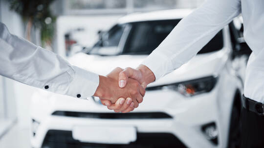 Close up of sales manager in black suit selling the car to the customer