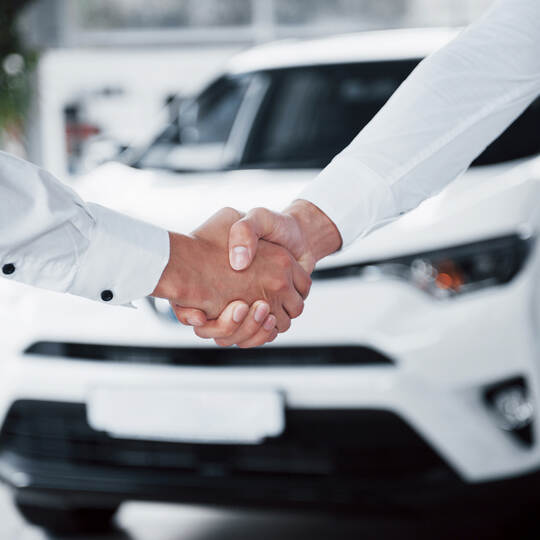 Close up of sales manager in black suit selling the car to the customer
