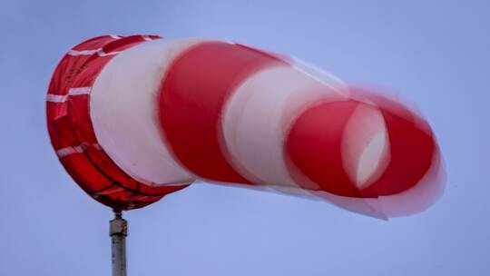 Windsack weht bei Regen und kräftigem Wind am Mast