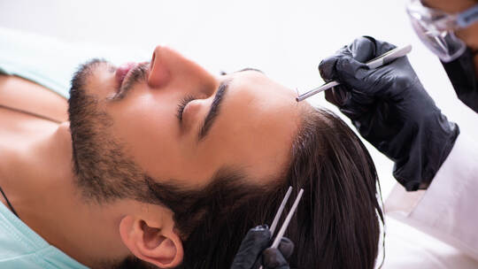 Young man visiting female beautician in hair transplantation con