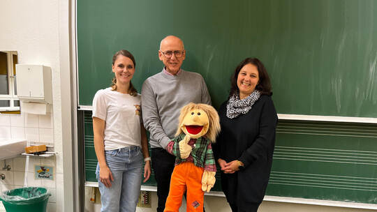 Pädagogin Eileen Schuhmacher, Rüdiger Schilling mit Puppe „Heini“ und Rektorin Tina Meduri (von links) informieren Eltern über d