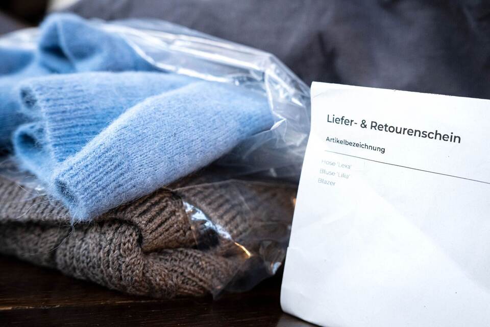Liefer- und Retourenschein liegt neben online bestellter Kleidung