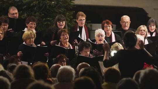 Vor dem Altar haben sich die Sängerinnen und Sänger des evangelischen Kirchenchors aufgestellt, alle Augen auf ihre Dirigentin S