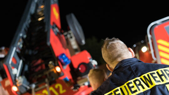 Symbolbild Feuerwehrmann vor Drehleiter