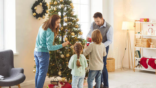Family Decorating A Tree For Christmas Or New Year At Home