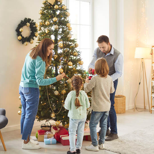 Family Decorating A Tree For Christmas Or New Year At Home