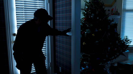 Burglar Breaking In To Home At Christmas Through Back Door