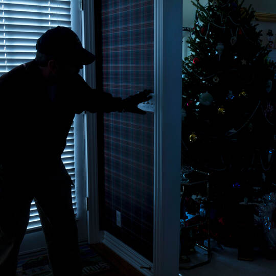 Burglar Breaking In To Home At Christmas Through Back Door
