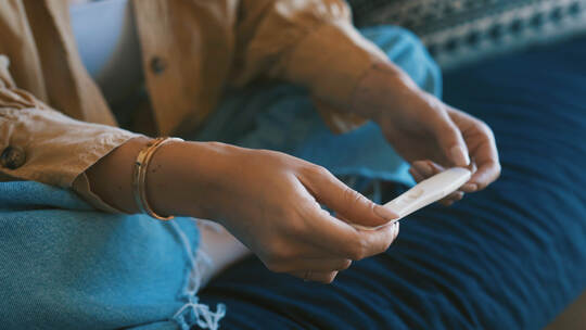 Pregnancy test, hands of woman and couch with check, maternity or hope in fertility outcome. Health, waiting and female person i