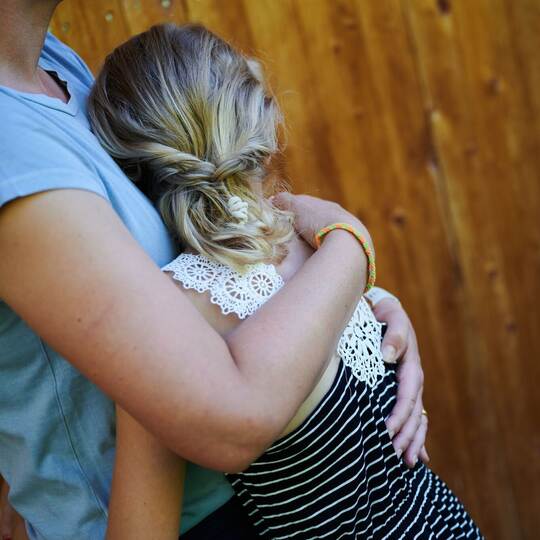 Ein Mädchen wird von seiner Mutter in den Arm genommen